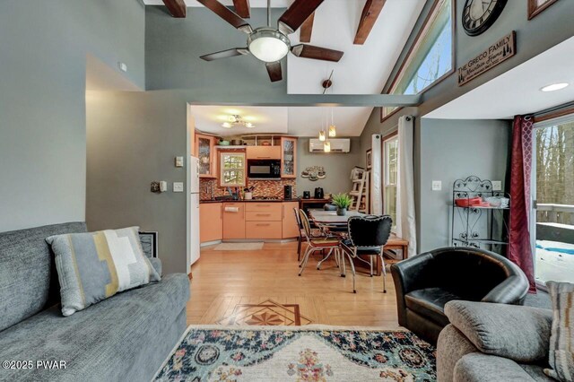 living room with high vaulted ceiling, beam ceiling, light hardwood / wood-style floors, and a wall unit AC