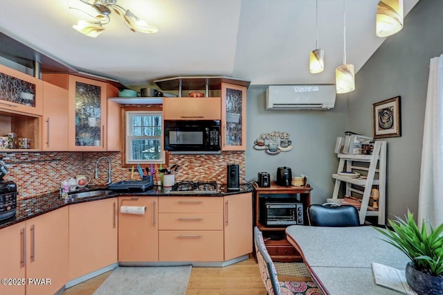 kitchen with sink, a wall unit AC, decorative backsplash, light brown cabinetry, and decorative light fixtures