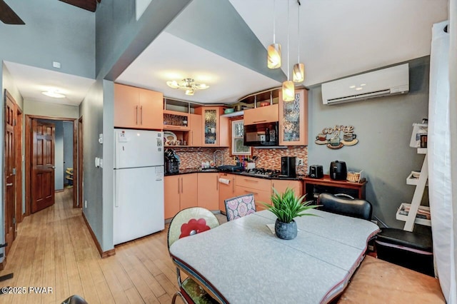 kitchen featuring light brown cabinetry, decorative light fixtures, a wall mounted AC, and white refrigerator