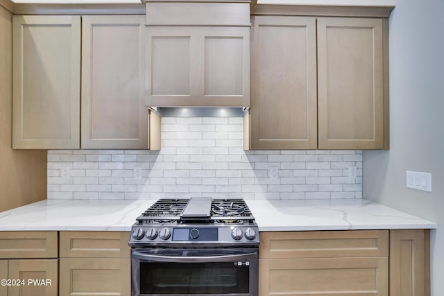 kitchen with black range with gas stovetop, light brown cabinetry, and tasteful backsplash