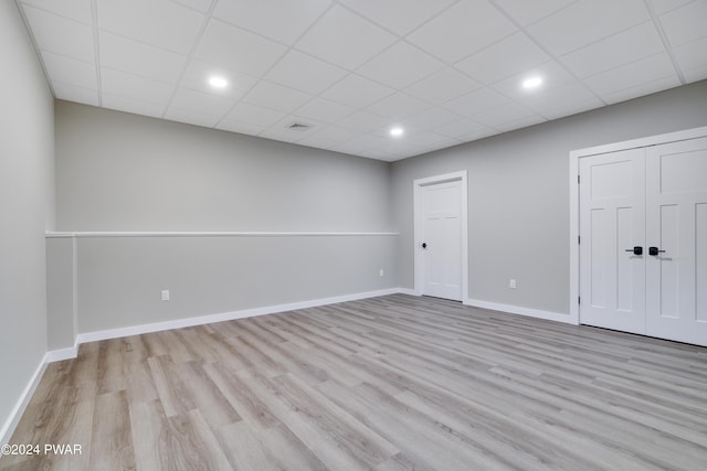 interior space featuring a drop ceiling and light hardwood / wood-style floors