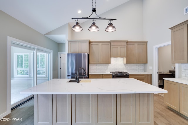 kitchen with a center island with sink, stainless steel fridge, black range with gas stovetop, and lofted ceiling