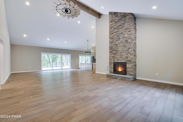 unfurnished living room featuring beam ceiling, a fireplace, high vaulted ceiling, and light hardwood / wood-style flooring