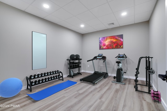 workout area featuring a drop ceiling and light wood-type flooring