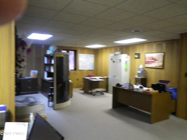 office space with a paneled ceiling, wood walls, and carpet floors