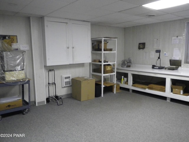 basement with a wall mounted air conditioner and a drop ceiling