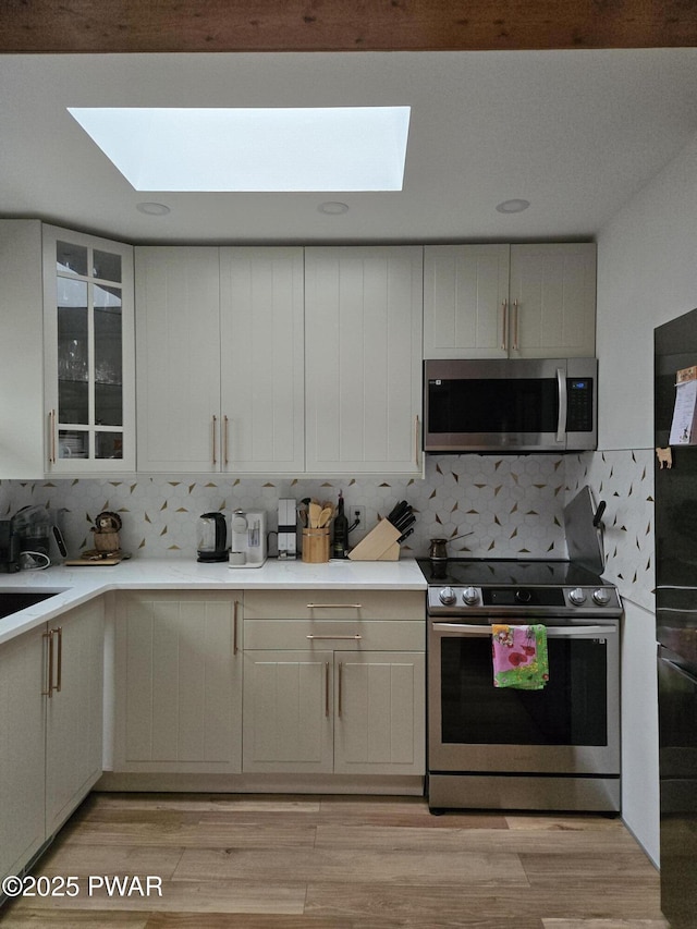 100 Saddlebrook Ln, Lords Valley, PA 18428 - kitchen with appliances with stainless steel finishes, a skylight, tasteful backsplash, and light wood-type flooring