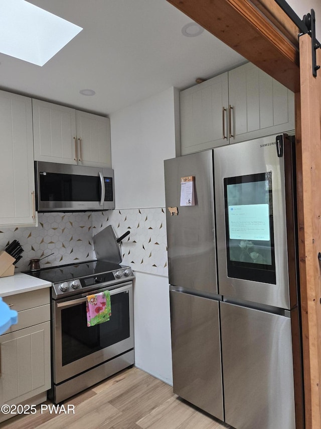 100 Saddlebrook Ln, Lords Valley, PA 18428 - kitchen featuring appliances with stainless steel finishes, tasteful backsplash, light countertops, light wood finished floors, and a skylight