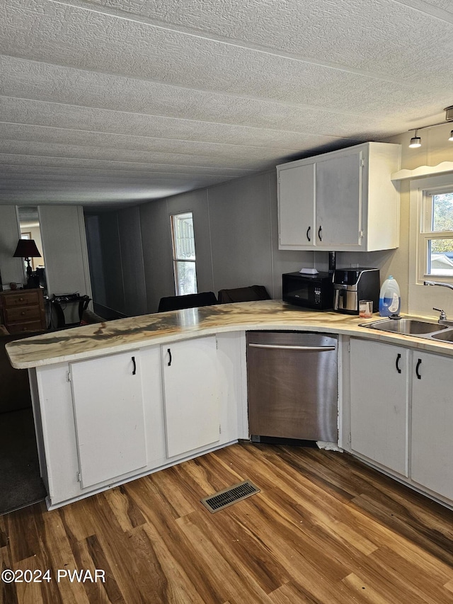 kitchen featuring hardwood / wood-style floors, white cabinets, sink, stainless steel dishwasher, and a textured ceiling