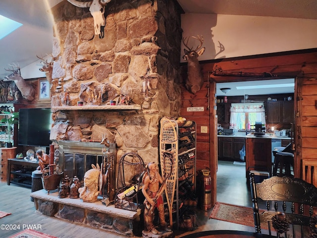 living room featuring hardwood / wood-style floors, vaulted ceiling, and a stone fireplace