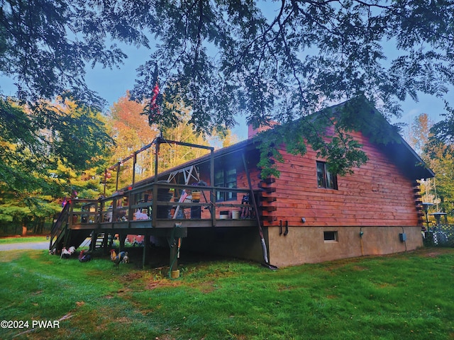 back house at dusk featuring a yard and a deck