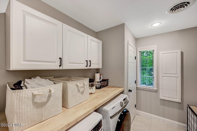 washroom featuring cabinets, light tile patterned floors, and washer and dryer