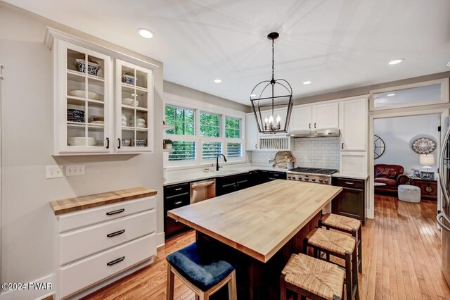 kitchen with wooden counters, a kitchen bar, pendant lighting, white cabinets, and a kitchen island