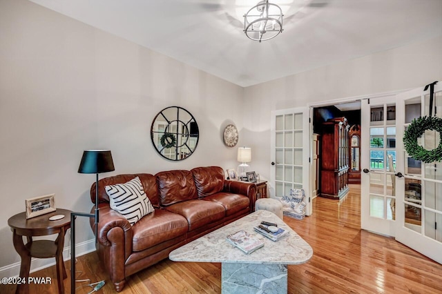 living room featuring french doors, light hardwood / wood-style floors, and a notable chandelier