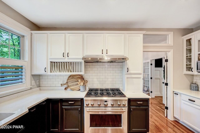 kitchen featuring tasteful backsplash, white cabinetry, light wood-type flooring, and appliances with stainless steel finishes