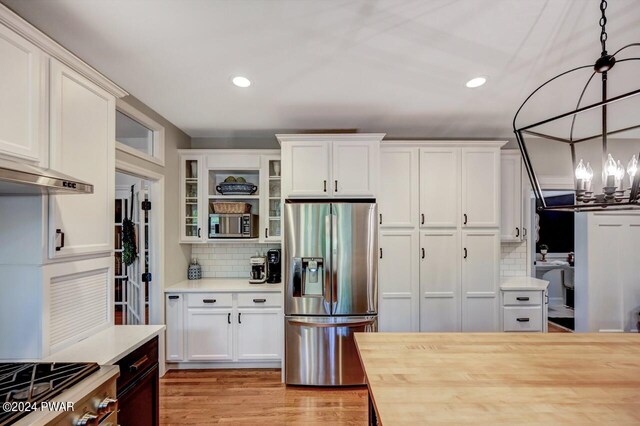 kitchen featuring decorative light fixtures, white cabinetry, stainless steel appliances, and tasteful backsplash