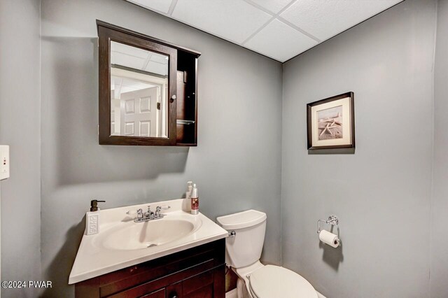 bathroom featuring a drop ceiling, vanity, and toilet