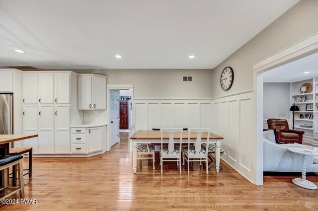 dining room featuring built in shelves and light hardwood / wood-style floors