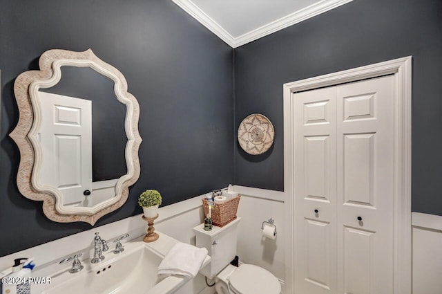 bathroom featuring toilet, crown molding, and sink