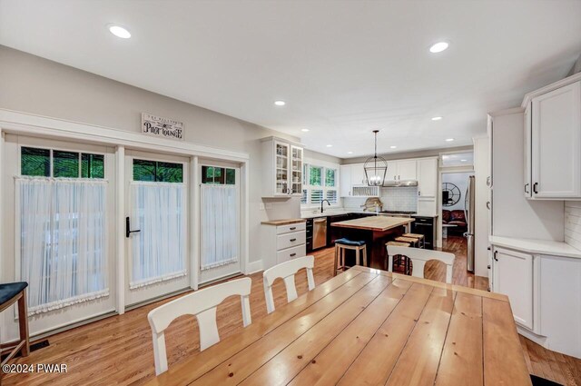 dining area with light wood-type flooring, a notable chandelier, and sink