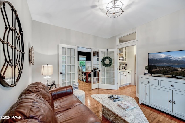 living room featuring french doors, light hardwood / wood-style floors, and an inviting chandelier