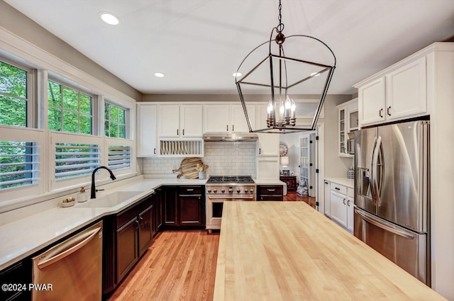 kitchen featuring pendant lighting, wooden counters, sink, a notable chandelier, and stainless steel appliances