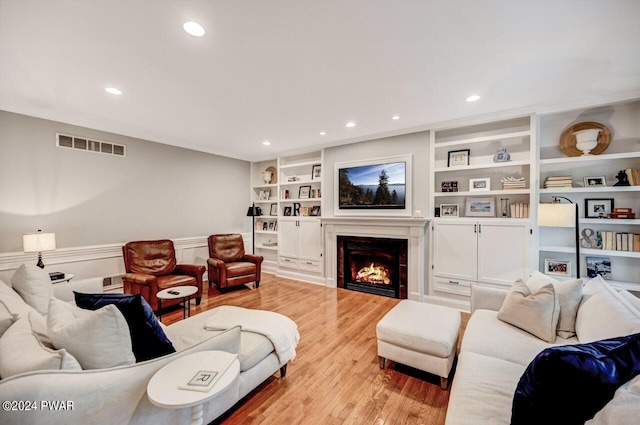 living room with built in features and light hardwood / wood-style flooring