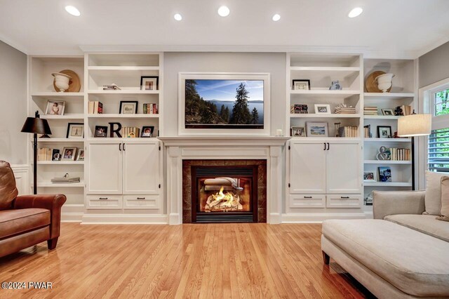 living area with built in shelves, a fireplace, and light hardwood / wood-style flooring