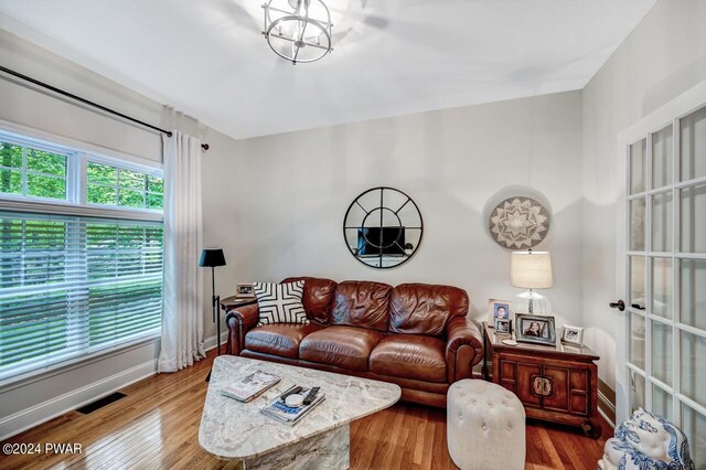 living room featuring wood-type flooring, a wealth of natural light, and a notable chandelier