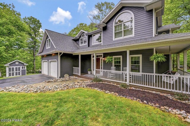 view of front of home featuring a storage unit, a porch, a garage, and a front yard