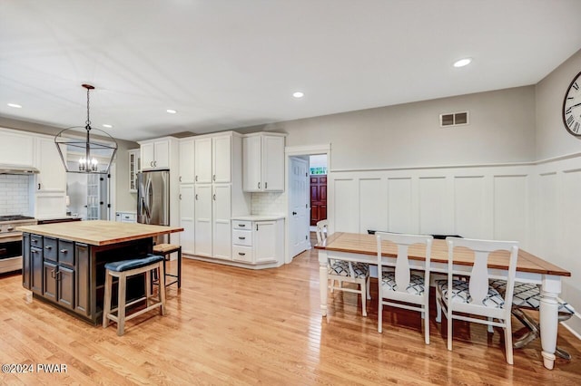 kitchen featuring wooden counters, white cabinets, tasteful backsplash, decorative light fixtures, and a kitchen island