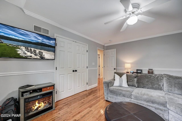 living room with ceiling fan, light wood-type flooring, and crown molding