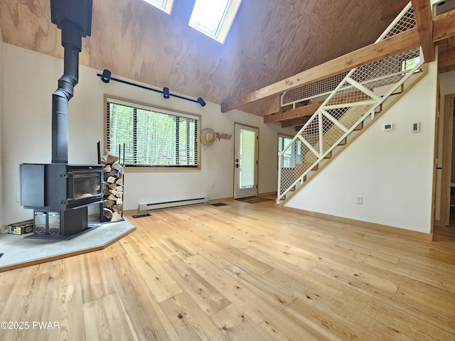 23 Highland Ln, Hawley, PA 18428 - unfurnished living room featuring a wood stove, a baseboard heating unit, wood-type flooring, stairway, and a skylight