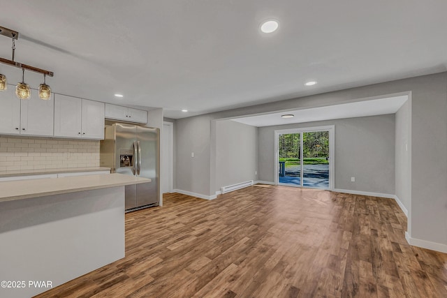 133 Neil Thompson Rd, Lackawaxen, PA 18435 - kitchen featuring stainless steel fridge, light countertops, a baseboard radiator, tasteful backsplash, and wood finished floors