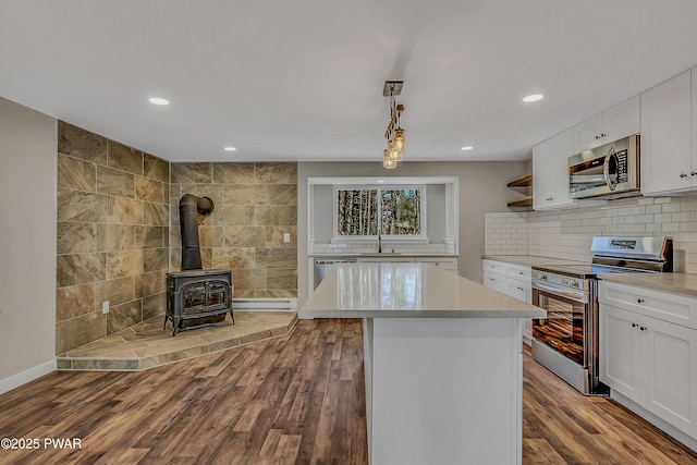 133 Neil Thompson Rd, Lackawaxen, PA 18435 - kitchen featuring appliances with stainless steel finishes, white cabinetry, a wood stove, dark wood-type flooring, and recessed lighting