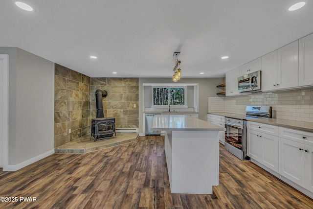 133 Neil Thompson Rd, Lackawaxen, PA 18435 - kitchen with stainless steel appliances, white cabinetry, a kitchen island, dark wood-style floors, and a wood stove