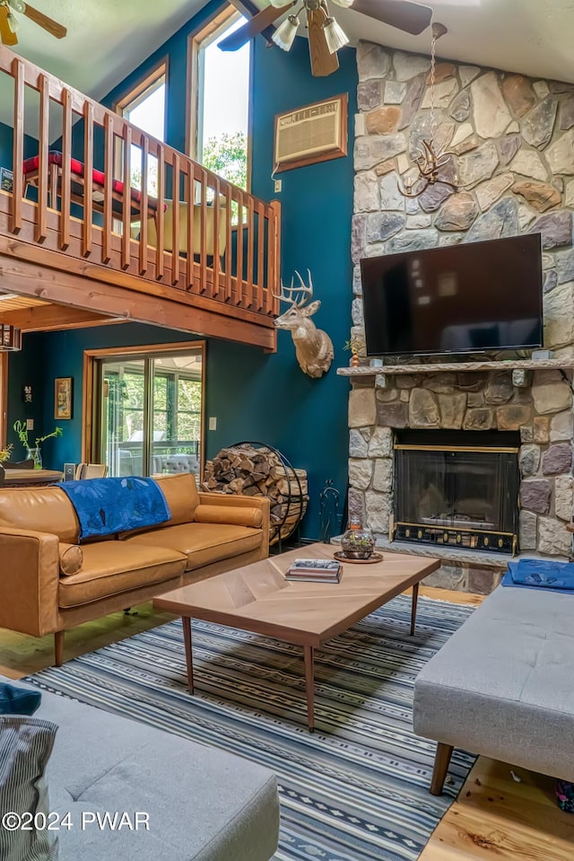 living room featuring an AC wall unit, ceiling fan, a fireplace, and a towering ceiling