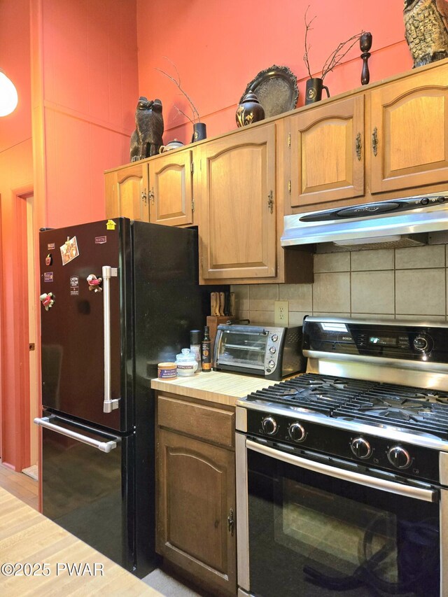 113 Widgeon Ln, Lords Valley, PA 18428 - kitchen featuring range with gas stovetop, under cabinet range hood, freestanding refrigerator, decorative backsplash, and light countertops