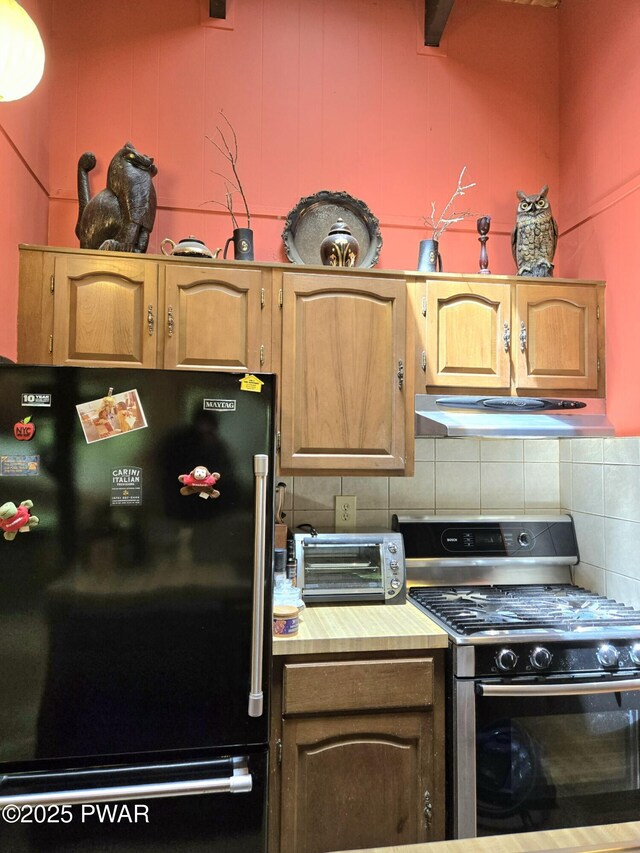 113 Widgeon Ln, Lords Valley, PA 18428 - kitchen with freestanding refrigerator, stainless steel gas range oven, under cabinet range hood, backsplash, and light countertops