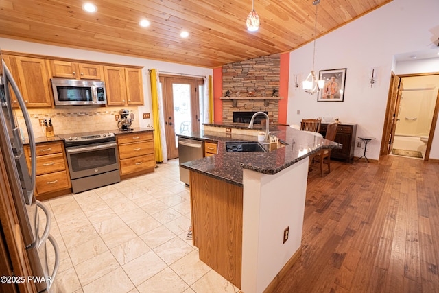 1010 Lotus Ter, Lake Ariel, PA 18436 - kitchen with appliances with stainless steel finishes, vaulted ceiling, a fireplace, wood ceiling, and decorative backsplash