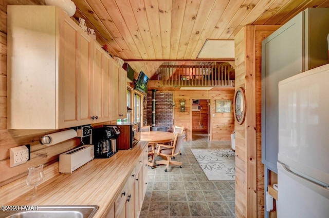 kitchen featuring wooden ceiling, wooden walls, and white fridge