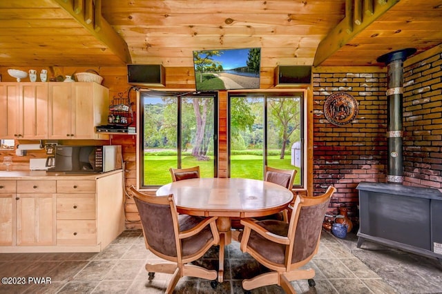 dining space featuring wood ceiling, a wood stove, brick wall, and vaulted ceiling