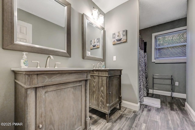 full bathroom featuring baseboards, wood finished floors, and vanity