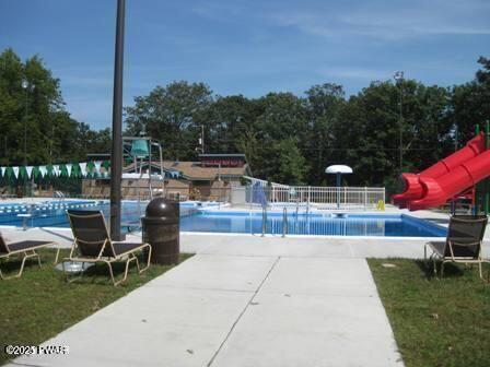 pool with fence, a water slide, and a patio