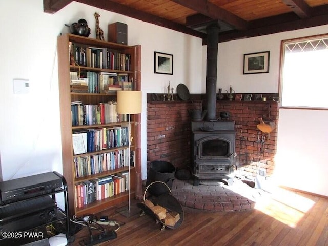 living area with a wood stove, wood ceiling, wood finished floors, and beamed ceiling