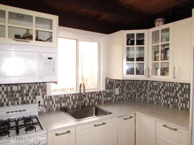 kitchen featuring light countertops, a sink, white appliances, and tasteful backsplash