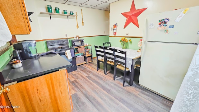 kitchen featuring black appliances, a paneled ceiling, and light hardwood / wood-style flooring