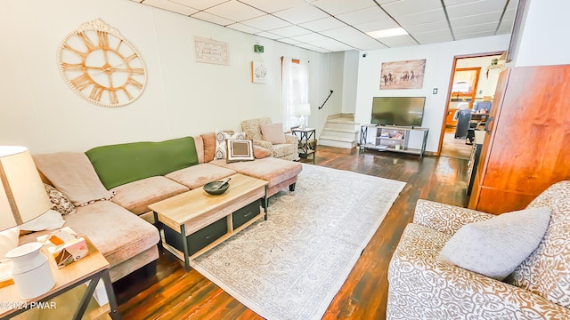 living room featuring dark hardwood / wood-style flooring and a drop ceiling