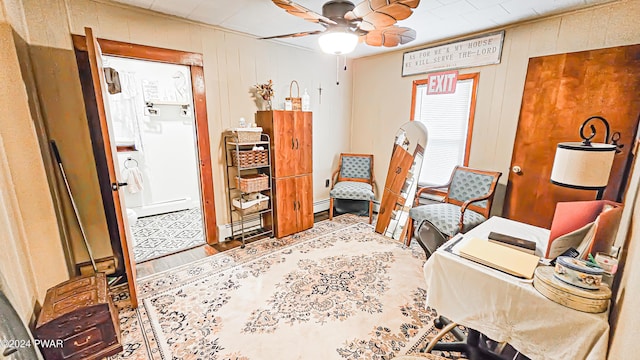 office space with baseboard heating, wood walls, and ceiling fan