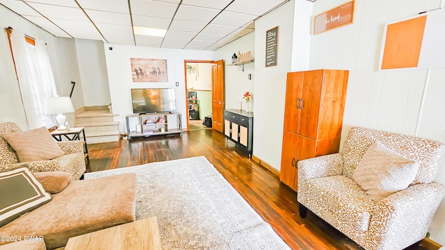 living room featuring a paneled ceiling and dark hardwood / wood-style floors